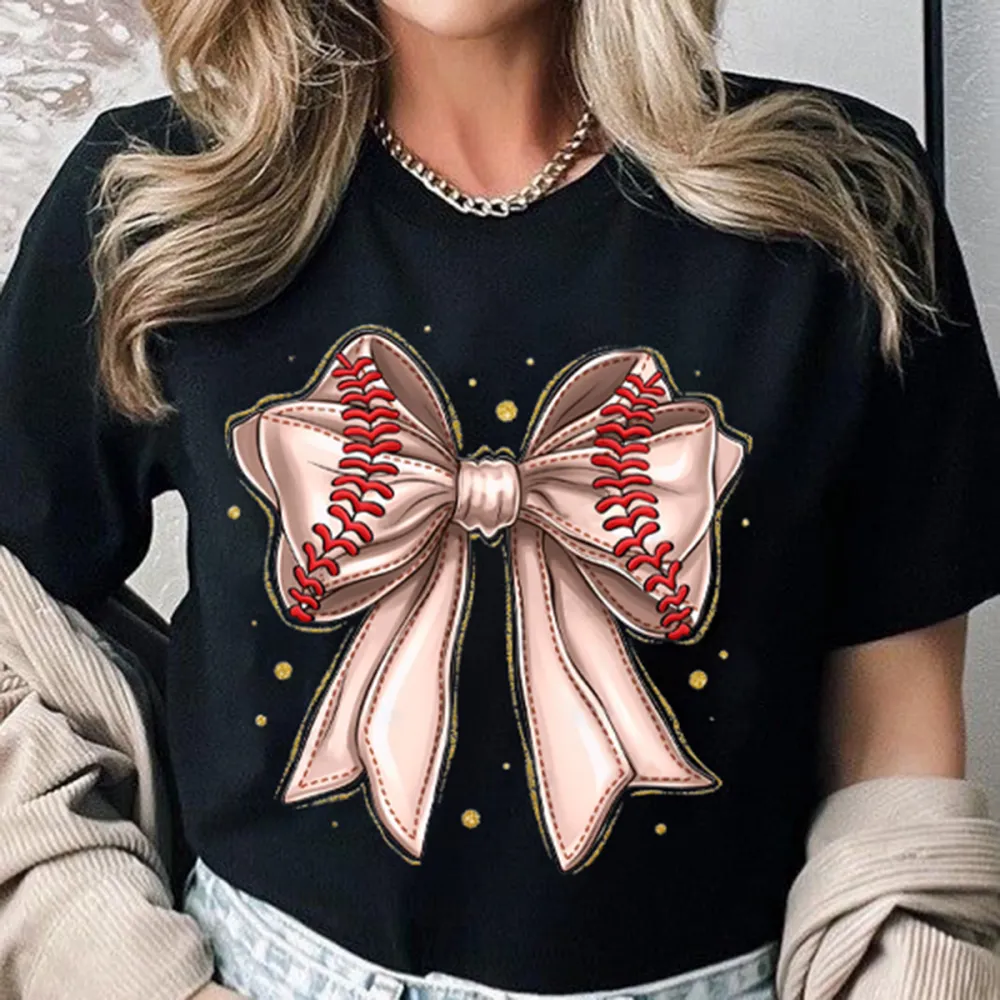 A Light Pink Bow Pattern With Red Baseball-Like Stitching Elements On The Edge Of The Bow And Some Gold Dots Around It, A Casual T-Shirt.