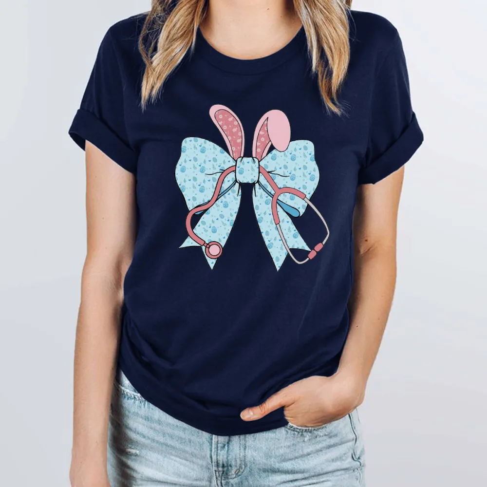 A Cartoon Rabbit Ear Element Bow Pattern, The Bow Has Blue Dots, The Rabbit Ears Are Pink With White Dots And A Pink Stethoscope Pattern, Casual T-Shirt
