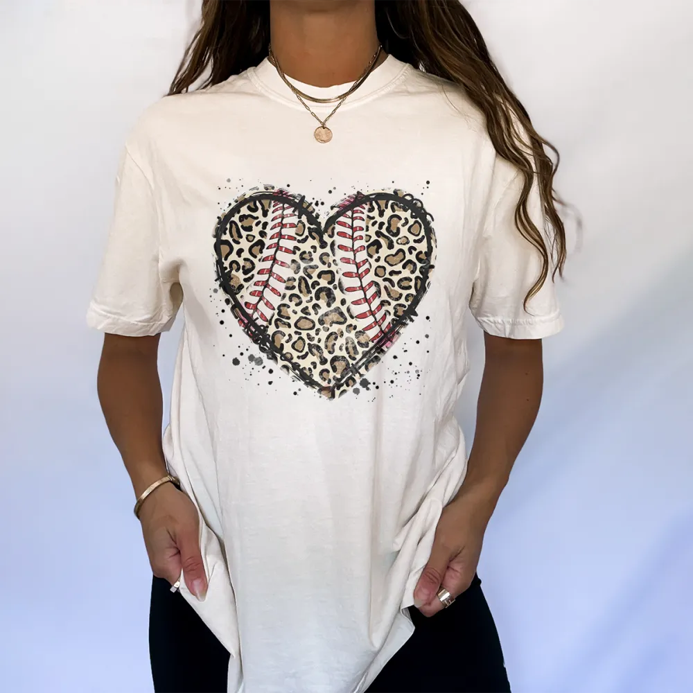 A Heart-Shaped Pattern With Baseball Stitching Elements Inside And Leopard Print, And Some Ink Splash Effects Around It, A Simple, Casual T-Shirt.