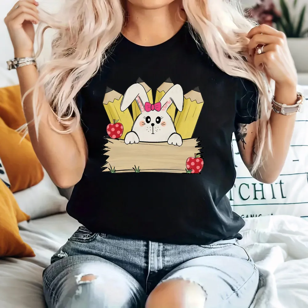 A Cartoon White Rabbit Wearing A Pink Bow Holding A Blank Board, A Yellow Pencil And A Red Strawberry With White Dots, A Childlike, Fresh Style, Casual T-Shirt