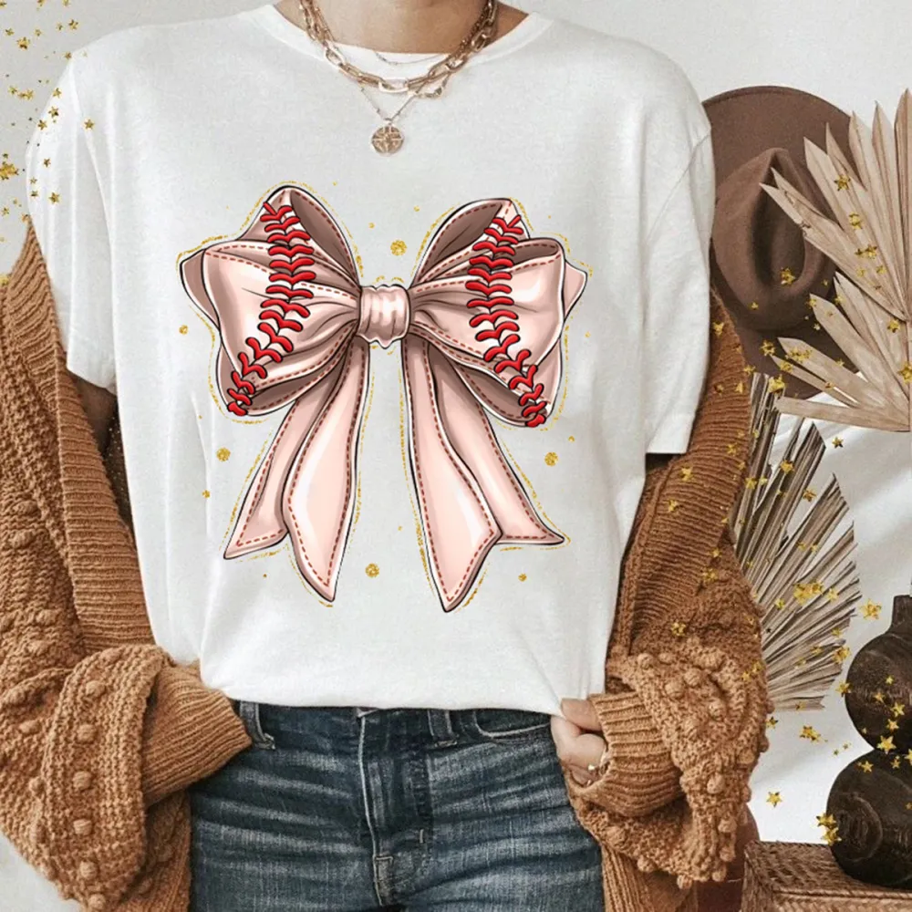 A Light Pink Bow Pattern With Red Baseball-Like Stitching Elements On The Edge Of The Bow And Some Gold Dots Around It, A Casual T-Shirt.
